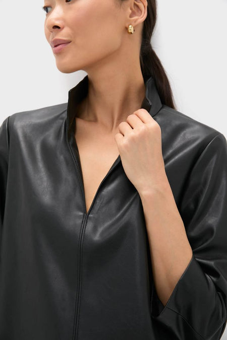 Woman wearing the Black Leather Clifton Dress with a stand collar and V-neckline, showcasing its classic and effortless style, paired with simple gold hoop earrings.