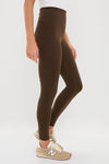Person in classic Chocolate Brown High Rise Compression Spandex MacKenzie Legging with beige New Balance sneakers, showcasing an effortless, high-end style suitable for any activity.