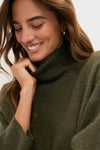 Young woman wearing the classic Moss Green Vivianne Dress, an effortless, high-end turtleneck sweater with a cozy, fun vibe, perfectly embodying Tuckernuck's style.