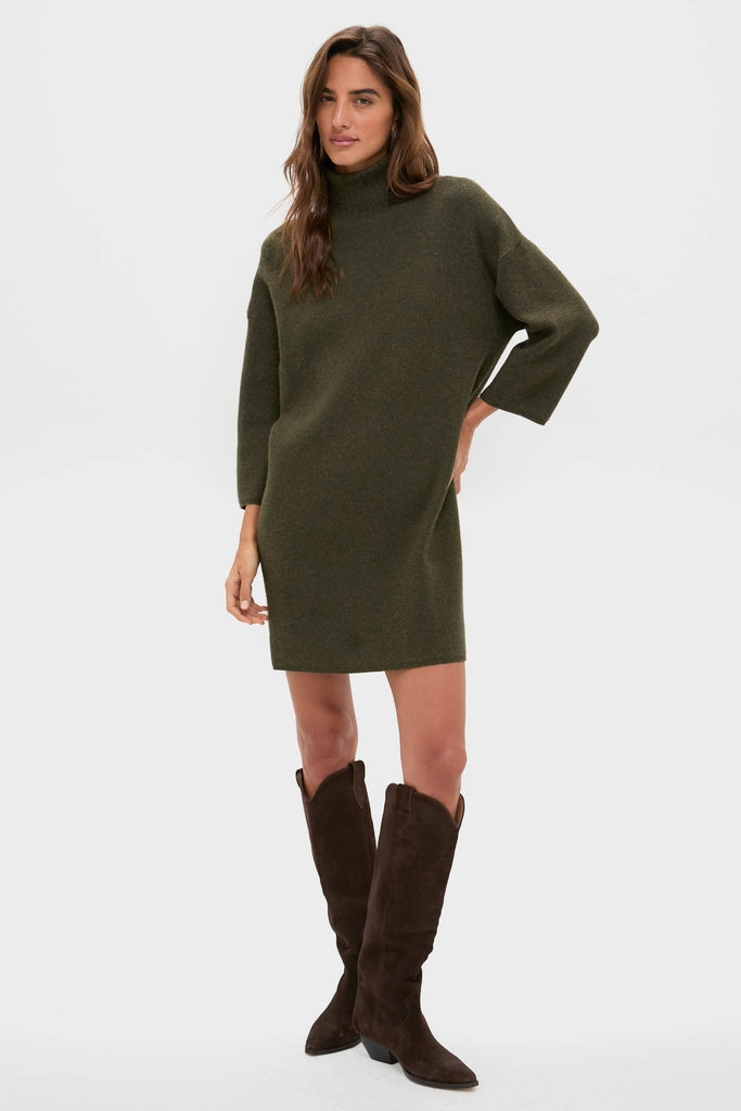 Woman modeling the classic Moss Green Vivianne Dress, an effortless long-sleeve sweater dress with a mock turtleneck, paired with high-end brown knee-high boots.