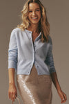 Young woman models the classic Ice Blue Cashmere Riley Cardigan, showcasing its effortless, high-end style paired with a fun, sequined skirt and round-handled bag.