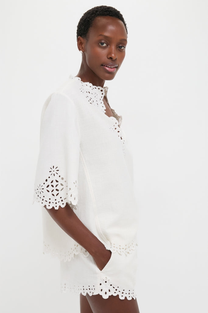 Woman modeling the classic White Shana Blouse, featuring effortless openwork embroidery and a relaxed fit, embodying a fun yet high-end style.