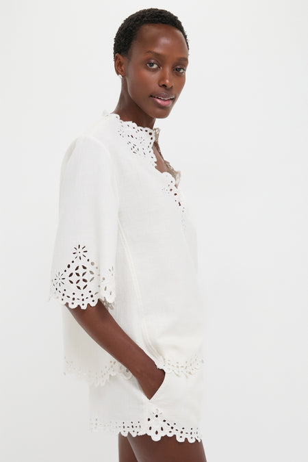 Woman modeling the classic White Shana Blouse, featuring effortless openwork embroidery and a relaxed fit, embodying a fun yet high-end style.