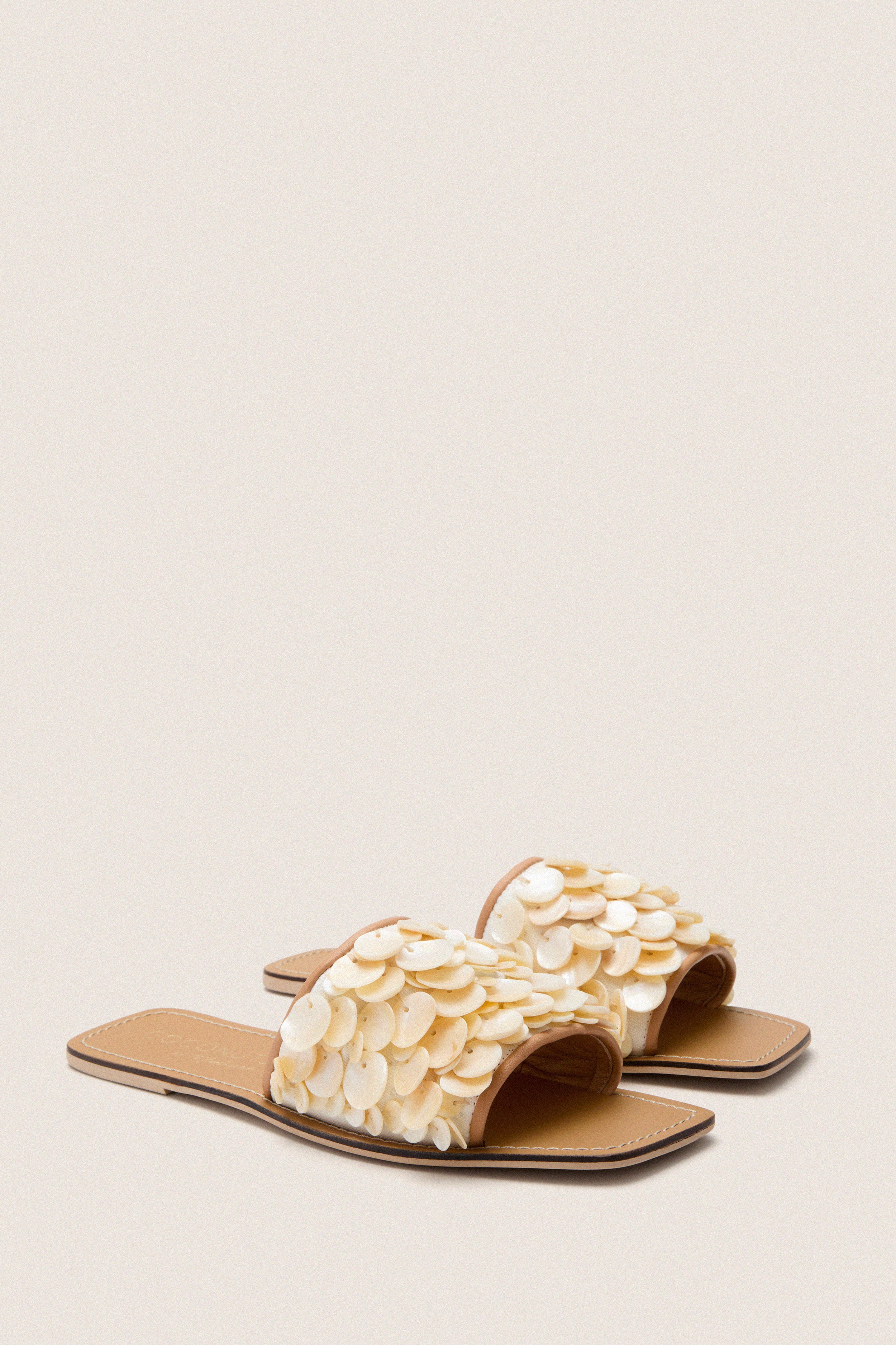Natural Waverly Sandals feature classic, shell-embellished straps on a flat sole, offering effortless, high-end style for fun summer outings.