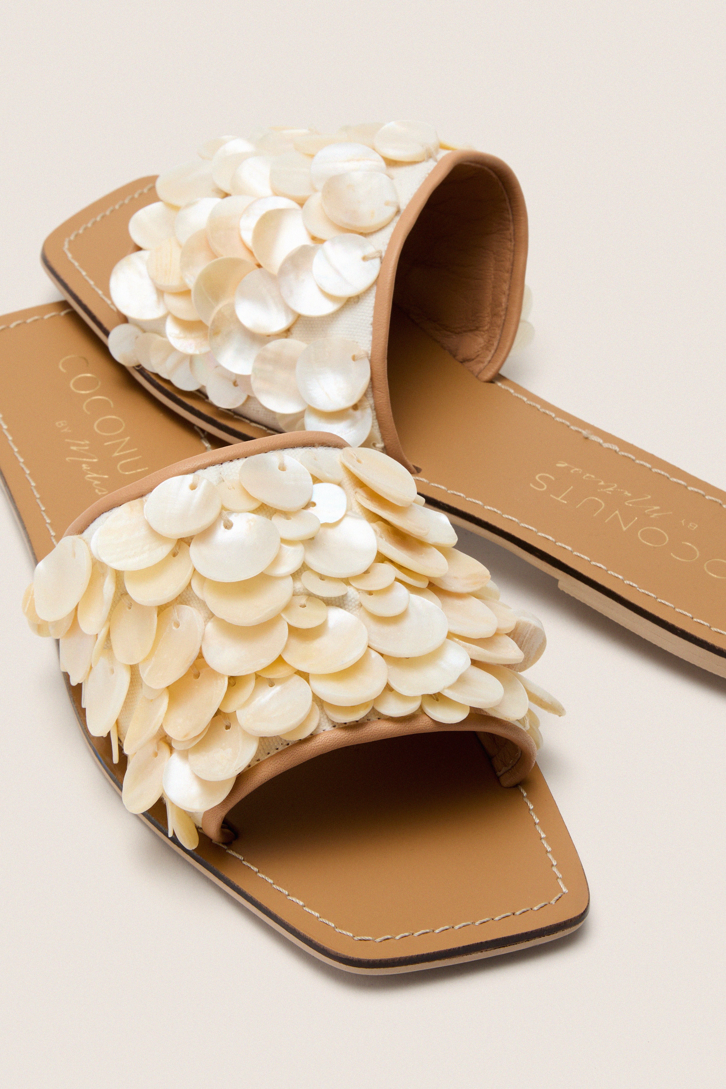 Natural Waverly Sandals feature classic, shell-embellished white straps and a flat sole, offering an effortless, high-end look perfect for fun, breezy summer outings.