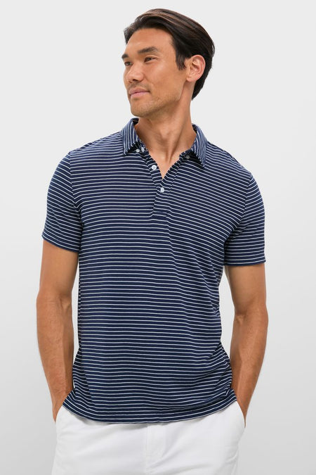 Man in classic, high-end Striped Navy Stretch Linen Polo, effortlessly styled with white pants, exudes fun and thoughtful elegance, embodying versatile, breathable, and minimalist design.