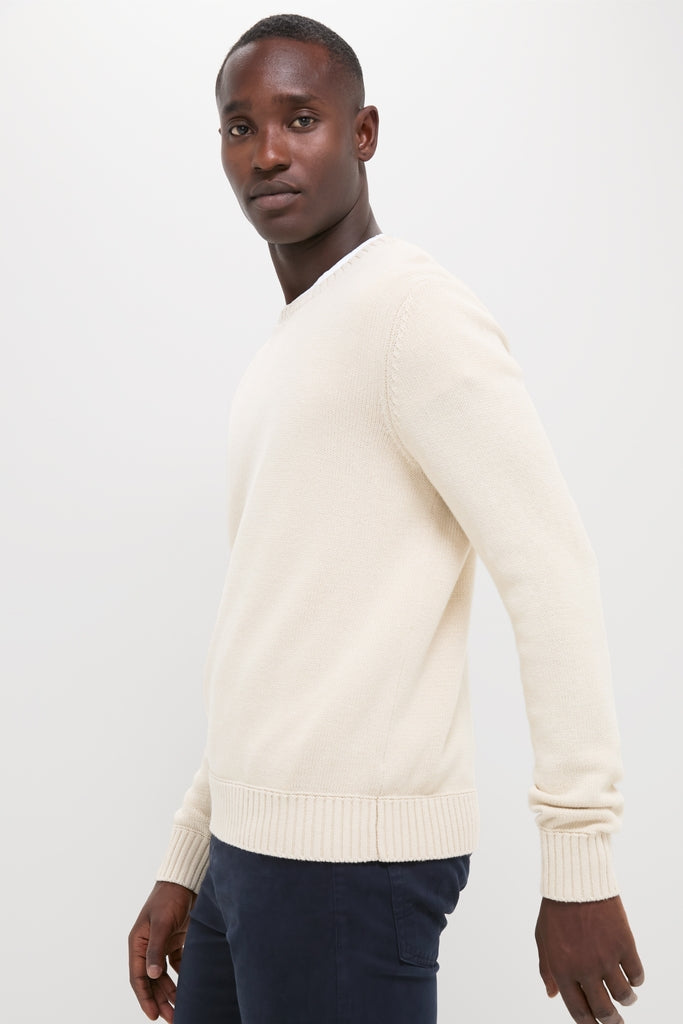 Model in a classic Light Tan All Season Classic Crewneck with ribbed details, embodying effortless, high-end style paired with dark navy trousers. Perfect for versatile, year-round wear.