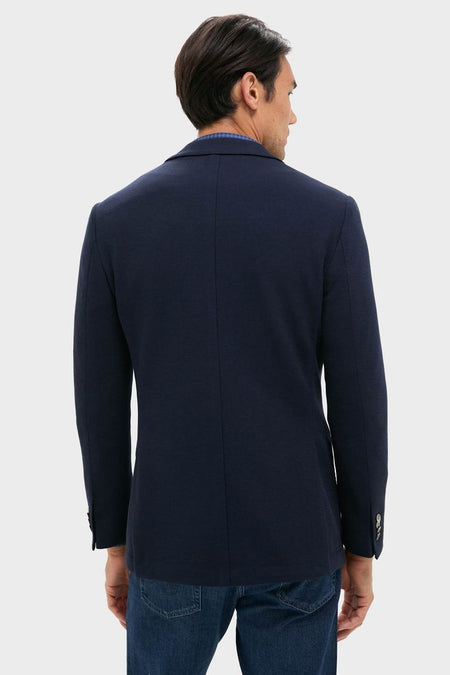 Back view of a person wearing the Navy Blue Knit Travel Blazer, showcasing its classic, effortless design perfect for high-end travel or business, paired with jeans.