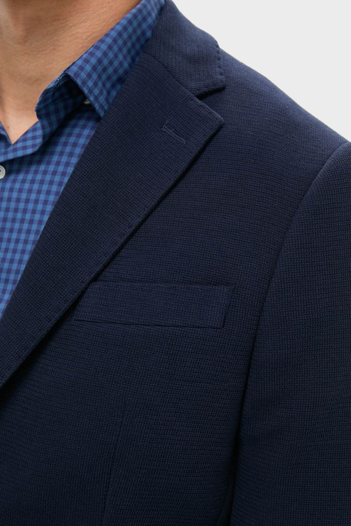 Classic and effortless, the Navy Blue Knit Travel Blazer features a textured design over a gingham shirt, perfect for high-end, fun business trips.
