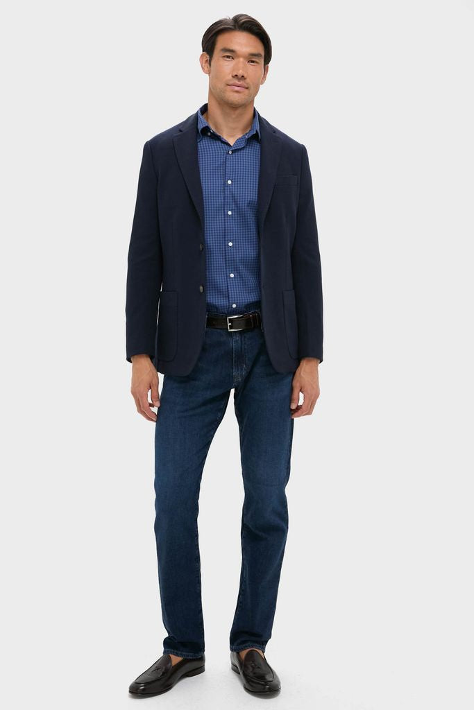 Man in Navy Blue Knit Travel Blazer with a blue checked shirt, dark jeans, and loafers, embodying a classic, effortless, and high-end style for business or travel.