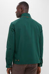 Man wearing the classic Dark Green Stanley Jacket, featuring buttoned tabs, suede-trimmed pockets, and a matte finish, paired with brown trousers for an effortless, high-end look.