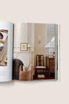 Artful Home open book showcases classic, effortless home decor with a marble mantel, wicker basket, and vintage furniture, embodying high-end design principles like palette and texture.