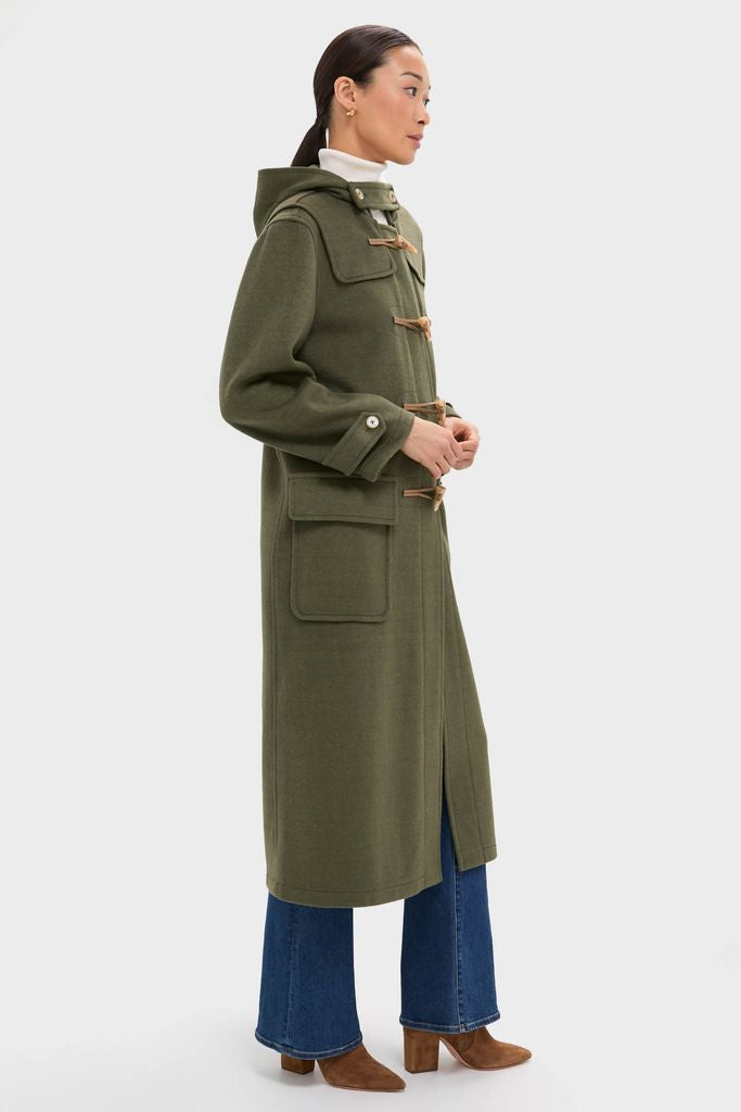 Model in an olive green Arthur Toggle Stadium Coat, featuring a hood, patch pockets, and toggle closures, paired with jeans and ankle boots for an effortless, high-end look.