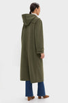 Person wearing the classic Olive Green Arthur Toggle Stadium Coat, featuring a hood and horn toggles, paired effortlessly with jeans and suede ankle boots for a high-end, fun look.