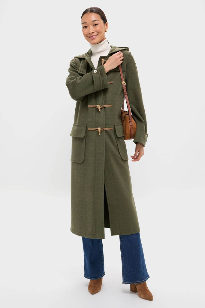 Woman in a classic, olive-green Arthur Toggle Stadium Coat with horn closures and patch pockets, styled effortlessly with jeans and cognac boots.
