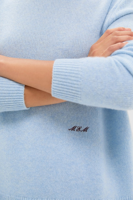 Wearing the Ice Blue Cashmere Bodie Boyfriend Crewneck, showcasing a classic, effortless style with ribbed cuffs and hem, featuring a subtle monogram for a high-end touch.