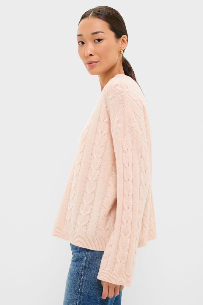 Woman models the Soft Pink Cashmere Eloise Cable Knit Sweater, showcasing its classic, effortless elegance with a relaxed, boxy fit and luxurious cashmere texture.