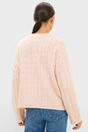 Back view of a model in a Soft Pink Cashmere Eloise Cable Knit Sweater, featuring a classic braided pattern and relaxed fit, paired with mid-blue jeans.