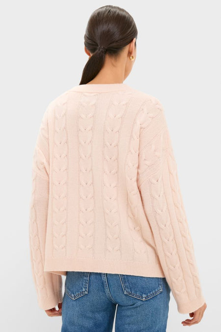 Back view of a model in a Soft Pink Cashmere Eloise Cable Knit Sweater, featuring a classic braided pattern and relaxed fit, paired with mid-blue jeans.