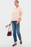 Person wearing the classic Soft Pink Cashmere Eloise Cable Knit Sweater, paired with mid-wash jeans and burgundy leather flats, exuding an effortless, high-end style.