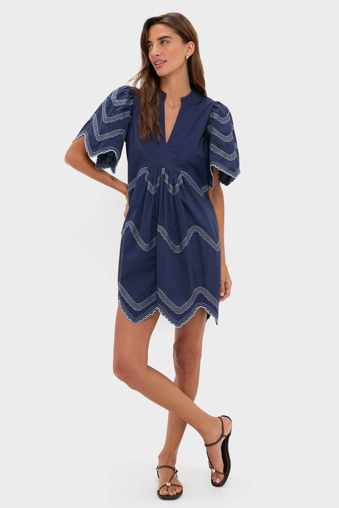 Woman models the classic Navy Embroidered Weston Mini Dress with scalloped edges and intricate detailing, embodying effortless, high-end style perfect for fun, versatile occasions.