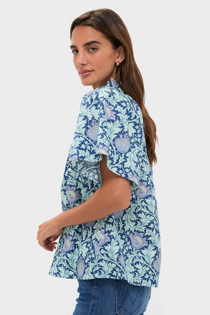 Model wearing the classic, high-end Multi Blue Leafy Floral Thea Blouse with ruffled collar and flare sleeves, paired effortlessly with medium-wash jeans for a fun look.