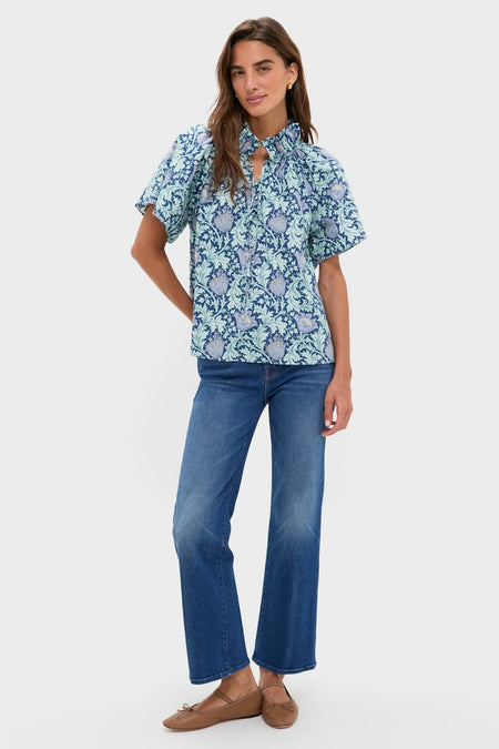 Model wearing the Multi Blue Leafy Floral Thea Blouse with ruffle collar and flare sleeves, paired effortlessly with blue jeans for a classic, high-end look.