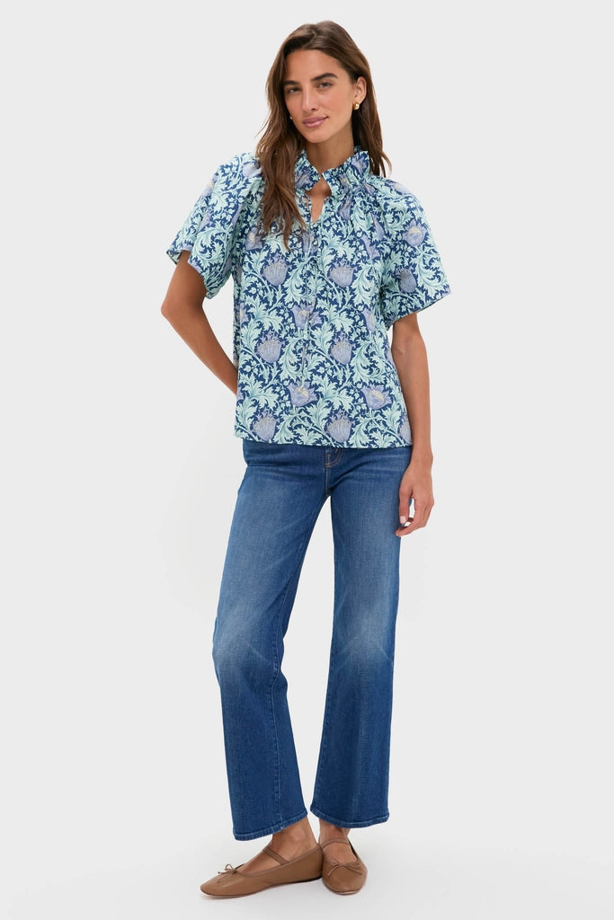 Model wearing the Multi Blue Leafy Floral Thea Blouse with ruffle collar and flare sleeves, paired effortlessly with blue jeans for a classic, high-end look.