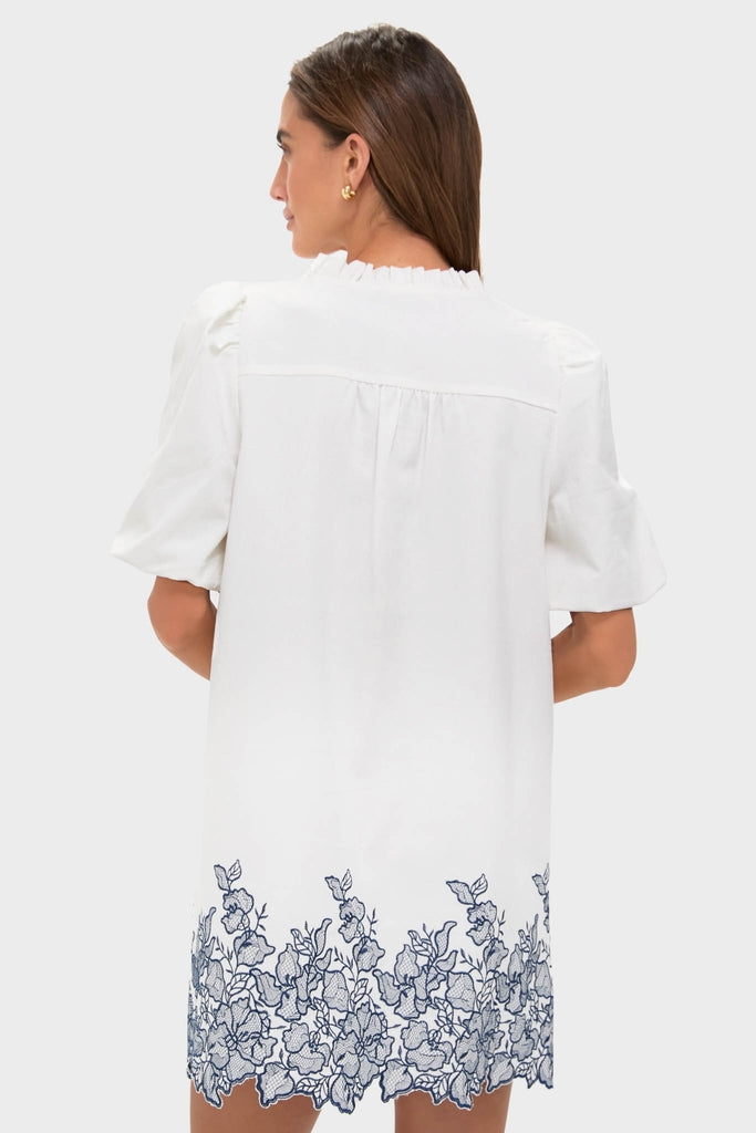 Woman in an effortless, classic White & Navy Embroidery Mimi Mini Dress with puff sleeves and embroidered hem, embodying fun and high-end style.
