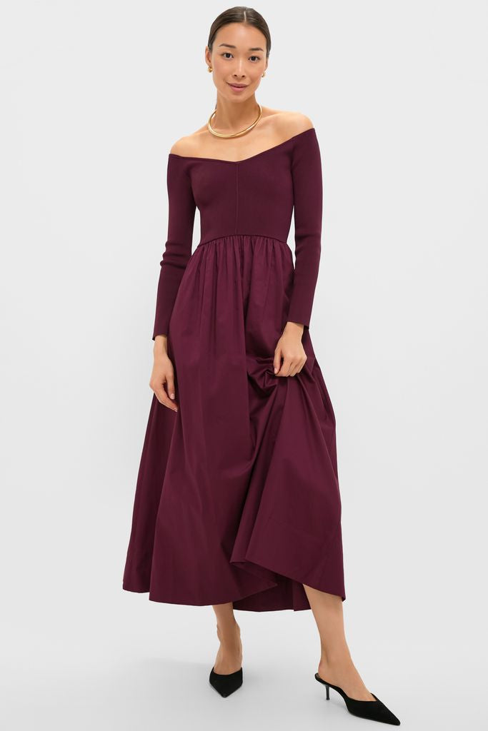 Model in Winetasting Clea Dress, a classic, off-the-shoulder gown with a gathered skirt, styled with gold accessories and mule heels for an effortless, high-end look.
