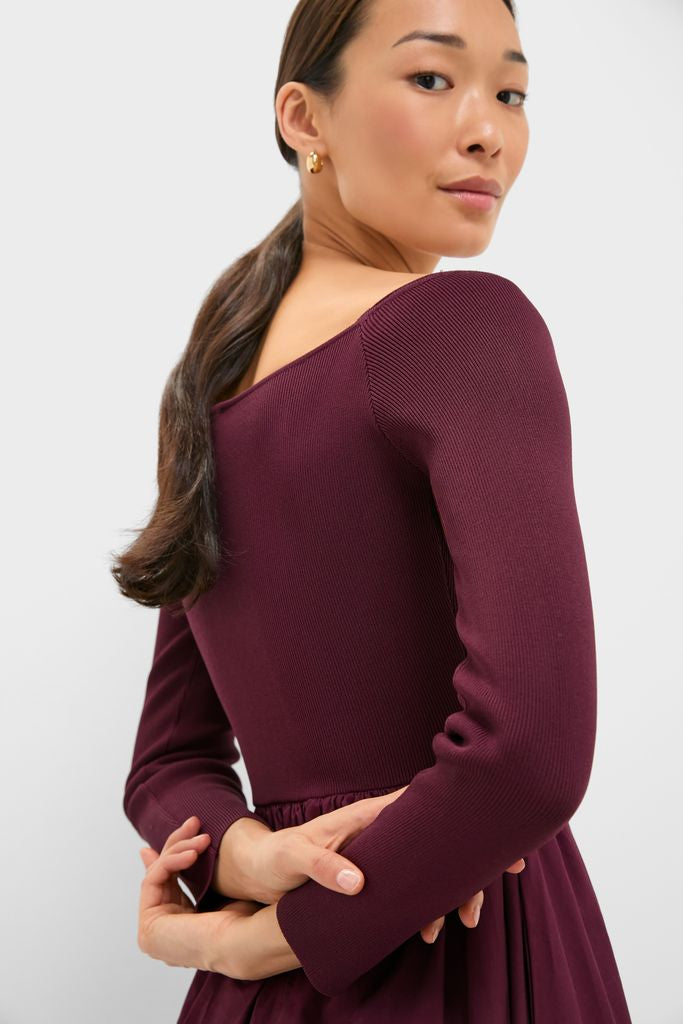 Woman in a studio wearing the Winetasting Clea Dress, an off-the-shoulder classic burgundy gown with a rib-knit design, embodying effortless elegance and high-end style.