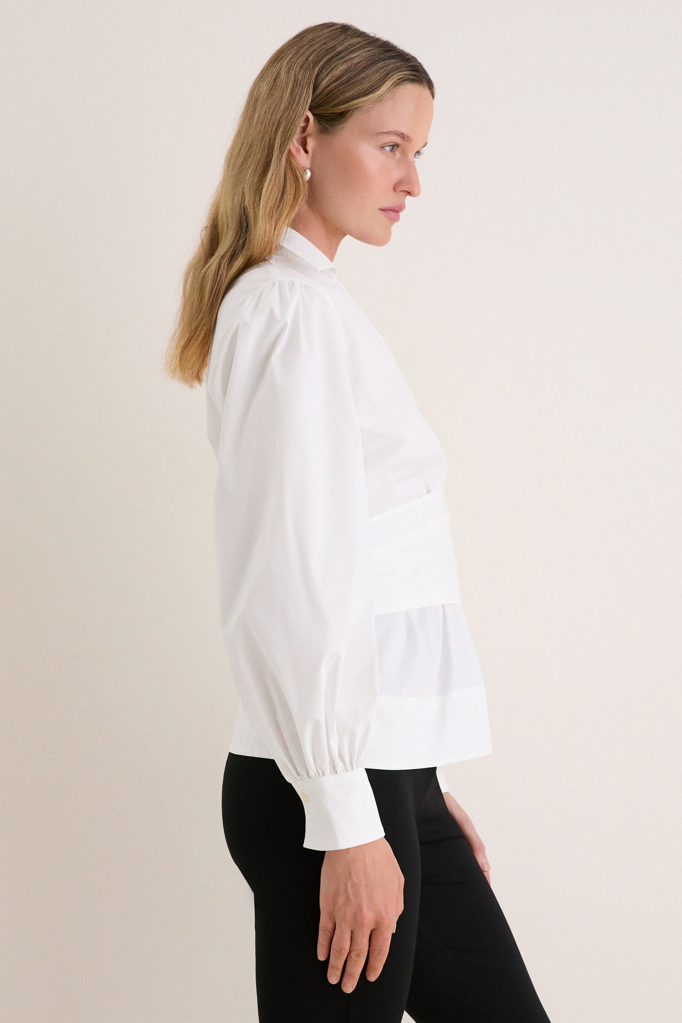 Side-profile of a woman in a classic, effortless White Tie Front Bow Bea Blouse with wrap silhouette, balloon sleeves, showcasing a high-end, fun style.
