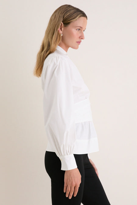 Side-profile of a woman in a classic, effortless White Tie Front Bow Bea Blouse with wrap silhouette, balloon sleeves, showcasing a high-end, fun style.