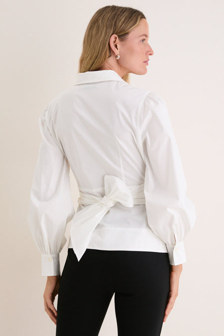 Fashion model wearing the classic White Tie Front Bow Bea Blouse with a chic sash bow at the back, paired effortlessly with slim-fit black pants.