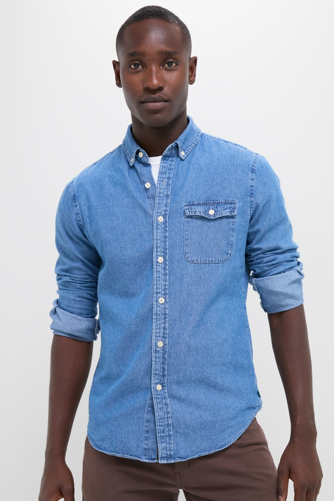 Person wearing Dark Indigo Washed Denim Shirt, sleeves rolled, paired with brown pants; a classic, high-end piece offering effortless style and fun versatility for year-round wear.
