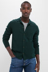 Young man models the classic Forest Green Merino Cardigan over a light gray T-shirt, embodying effortless, high-end style with its fun, versatile knit design.