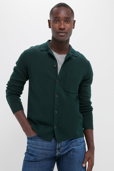 Young man models the classic Forest Green Merino Cardigan over a light gray T-shirt, embodying effortless, high-end style with its fun, versatile knit design.
