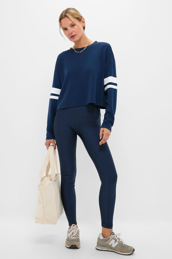Woman models the Navy Varsity Comfort Stretch Matilda Pullover with white striped sleeves, exuding a classic, effortless style. Perfect for high-end, fun outings.