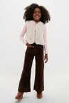 Young girl models a classic, high-end Cream Teddy Vest by BONTON, layered over a pink top, embodying effortless, fun style with corduroy pants and boots.