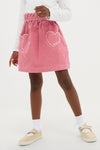 Child wearing classic Pink Douchka Skirt with heart-shaped pockets, paired with ruffled socks and glitter Mary Janes, embodying an effortless and fun high-end style.