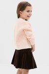 Young girl in classic Light Pink Heart Sweater, exuding effortless style and fun, paired with a dark brown corduroy skirt, embodying high-end winter fashion.