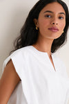 Woman wearing the classic White Wrenli Shortsleeve Pleated Top, showcasing effortless style with subtle pleats and a notched neckline, exuding high-end, fun elegance.