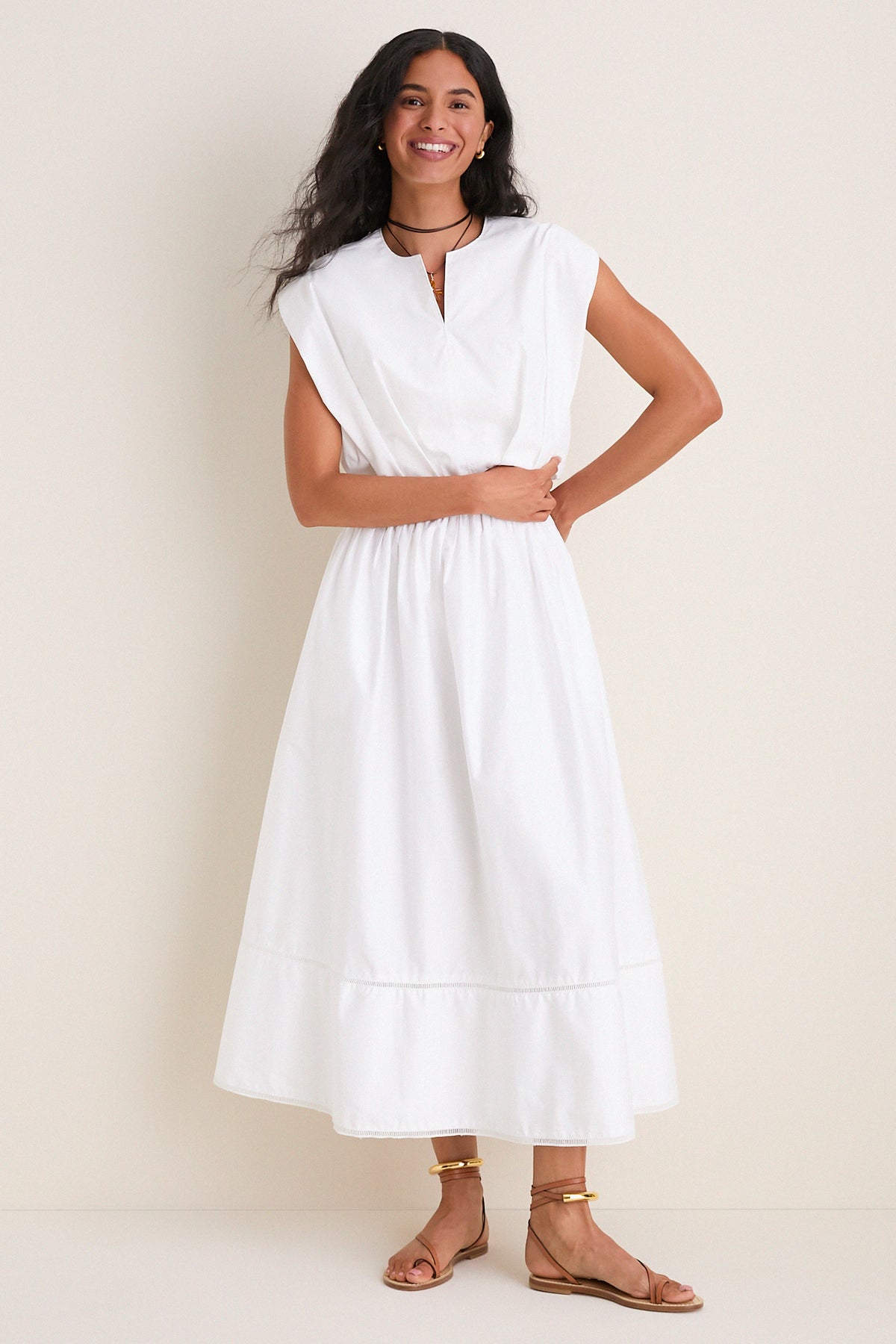 Young woman models the classic White Wrenli Shortsleeve Pleated Top, embodying effortless polish with cap sleeves, a split v-neck, and pleated hem for high-end, fun style.