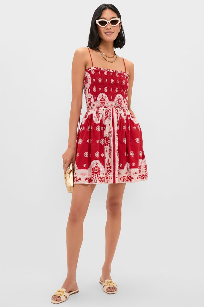 Model in Merida Lava Bandana Dress, a classic, high-end mini dress with smocked bodice and adjustable straps, styled with sunglasses, gold accessories, and sandals for an effortless, fun look.