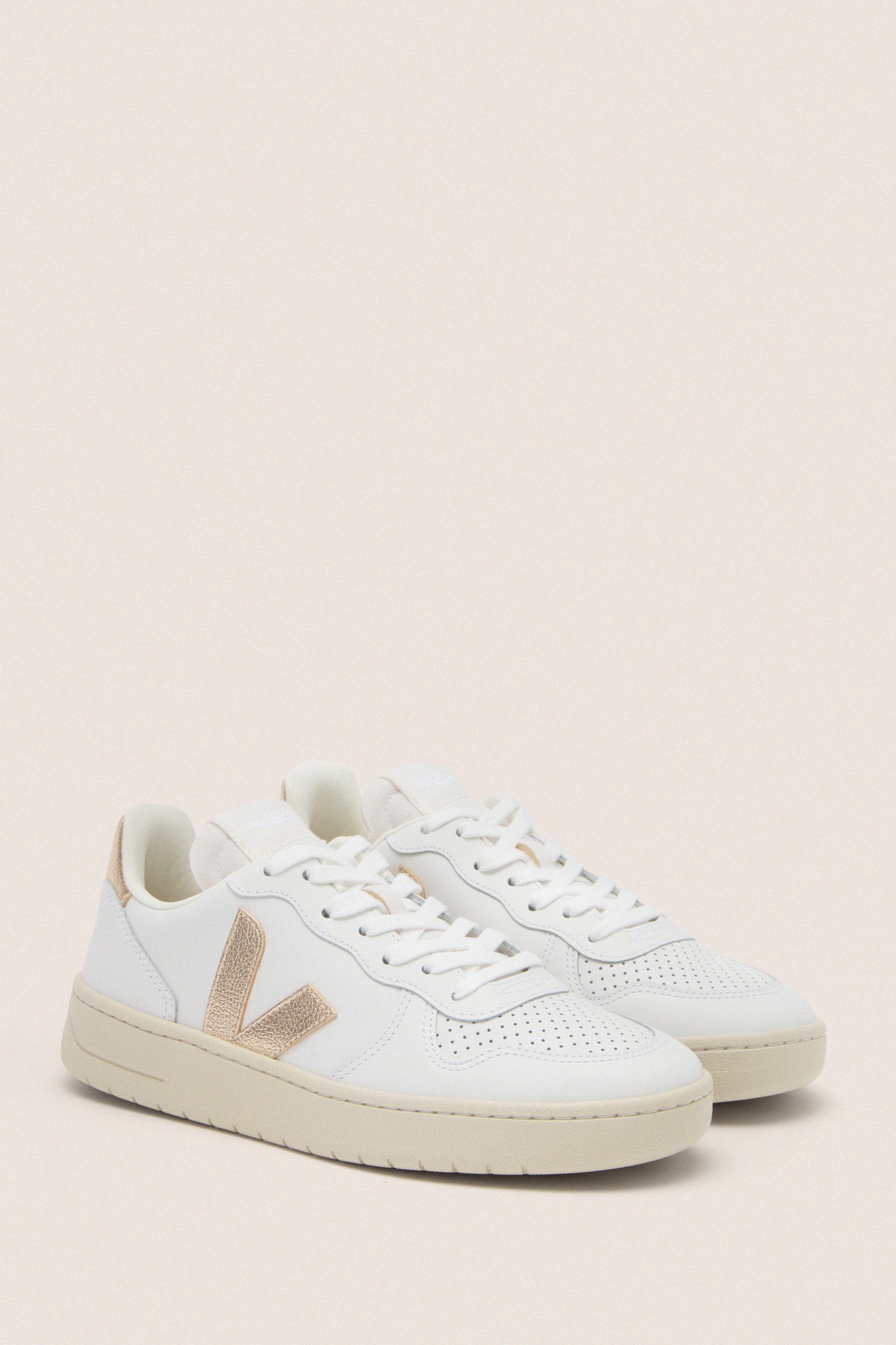 Extra White Platine V-10 Sneakers: Classic low-top white leather sneakers with perforated details, metallic gold V logo, and an off-white sole for an effortless, high-end look.