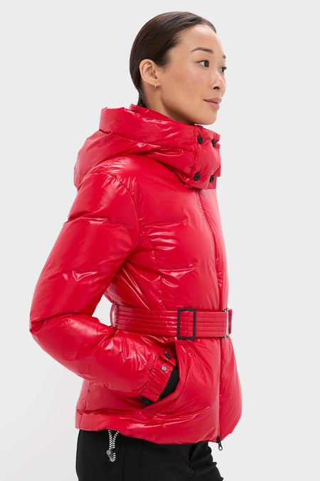 Profile view of a person wearing the Red Candice Ski Parka, a high-end, shiny puffer jacket with a belt and hood, embodying effortless, classic style and fun functionality.