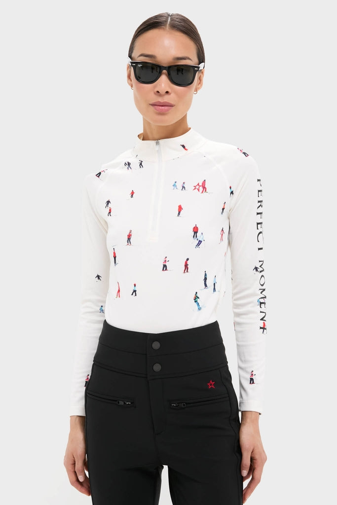 Model in the Dede Ski Print 1/4 Zip Base Layer Top, showcasing classic, effortless style. Long-sleeve top with skiing motifs, paired with black high-waisted pants.