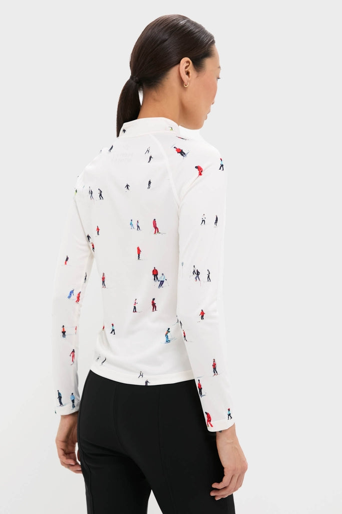 Woman in fitted black pants models the Dede Ski Print 1/4 Zip Base Layer Top, showcasing its classic, effortless style with fun minifigure prints and high-end performance features.