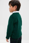 Young boy in profile wearing the Forest Green Bromo Merino Boy Jumper, a classic, high-end sweater with effortless style, featuring buttons and ribbed finishes for a fun, timeless look.