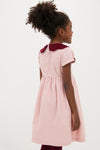 Young girl in profile wearing the Pink Julieta Girl Dress; a classic, high-end, and fun fit-and-flare design with a velvet scalloped collar and burgundy tights.